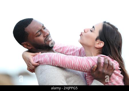 Ritratto di vista laterale di una donna che cerca di baciare un uomo che la allontana Foto Stock