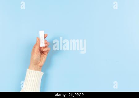 Dispositivo di prova Coronavirus Covid-19 femmina con tenuta di mano rapida con risultato negativo su sfondo azzurro Foto Stock