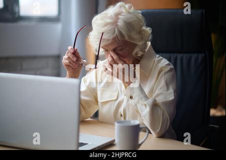 Donna togliendo gli occhiali che toccano gli occhi chiusi Foto Stock
