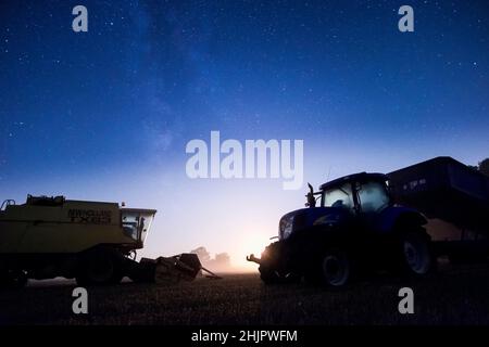 Mietitrebbia e trattore di notte con cielo stellato e luna di regolazione  Norfolk UK Foto Stock