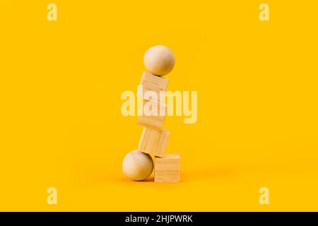 Blocchi di legno e palle in un mucchio su sfondo giallo Foto Stock