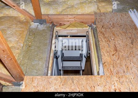 Scale in metallo scorrevoli fino all'attico nel soffitto, anta aperta e scale aperte, aspetto moderno. Vista dalla cima delle scale in basso. Foto Stock