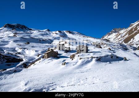 case in pietra circondate da neve bianca nei pressi di dondena, nell'inverno delle alpi italiane Foto Stock