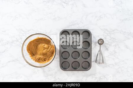 Foderare la teglia per cupcake con i rivestimenti per cupcake in lamina per cuocere i cupcake di pan di zenzero. Foto Stock