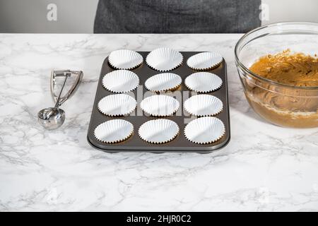 Foderare la teglia per cupcake con i rivestimenti per cupcake in lamina per cuocere i cupcake di pan di zenzero. Foto Stock