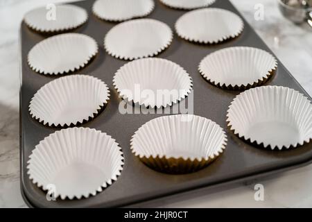 Foderare la teglia per cupcake con i rivestimenti per cupcake in lamina per cuocere i cupcake di pan di zenzero. Foto Stock