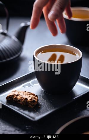 Biscotti con pezzetti di cioccolato e tè su sfondi diversi e in tazze diverse Foto Stock