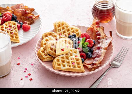 Colazione di San Valentino con waffle a forma di cuore, pancetta e frutti di bosco Foto Stock