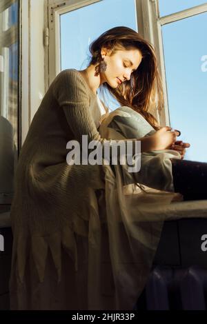 Donna seduta sul davanzale in un abito Foto Stock