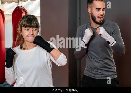 Insegnante di boxe che insegna a una donna matura come fare a box Foto Stock