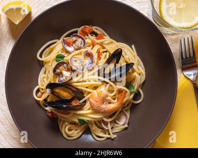 Piatto di spaghetti allo scoglio vista dall'alto. Spaghetti con frutti di mare su sfondo blu. Cucina italiana, pasta con gamberi e cozze, vongole. Mediterraneo Foto Stock