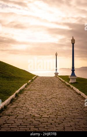 Splendida vista al tramonto su una piccola strada di mattoni con lampioni Foto Stock