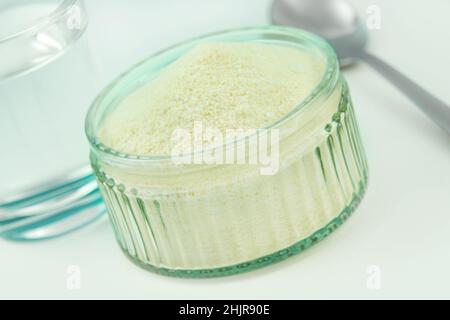 Collagene in polvere e bicchiere d'acqua con cucchiaio Foto Stock