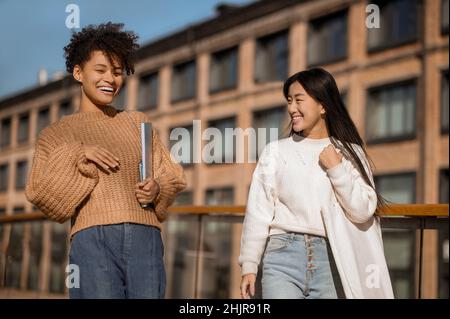 Ragazza asiatica che guarda parlare ragazza mulatto Foto Stock