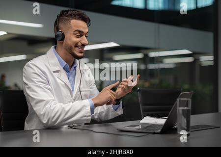 Bel giovane scienziato medio-orientale che usa il laptop in ufficio Foto Stock