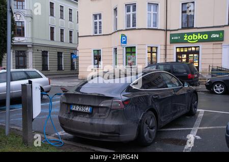 Jelenia Gora, Polonia - 15 gennaio 2022. Una foto statica di una ricarica a doppio motore Tesla Model 3 nera alla stazione di ricarica CA in un inverno soleggiato Foto Stock