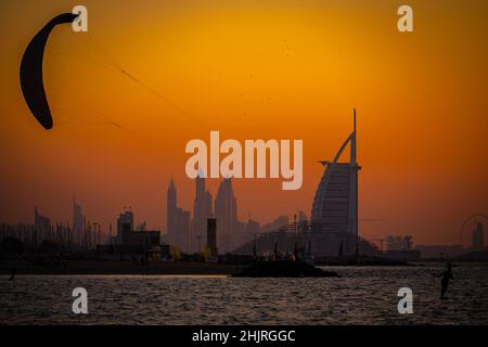 Silhouette kite surfer durante il tramonto dorato con il Burj al Arab sullo sfondo, carta da parati Dubai Foto Stock