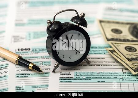 Dollari americani con orologio sopra il modulo di imposta individuale Foto Stock