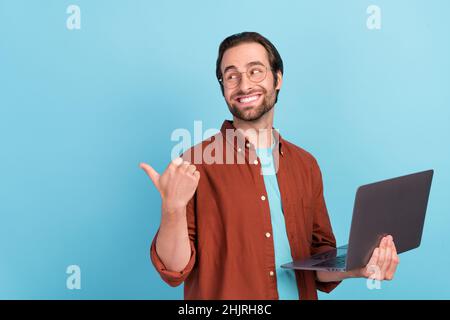 Foto del manager brunet giovane ragazzo tenere laptop indice promo indossare occhiali trend fit isolato su sfondo blu Foto Stock