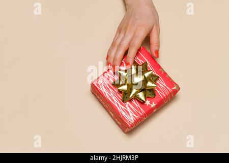 Una mano della donna raggiunge per una scatola regalo rossa con un arco giallo, un posto per il testo per copiare spazio. Foto Stock