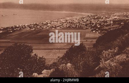 Sotto il Monte Carmelo con la città scintillante di Haifa che giace oltre sulla riva curvilinosa presso la baia aperta di Acre. Israele. Palestina (1923) Foto Stock