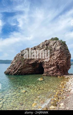 Paesaggio con solitaria formazione rocciosa in mare o oceano. Bella roccia vicino alla costa contro il cielo blu, immagine verticale Foto Stock