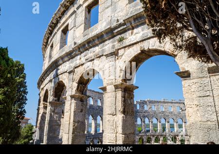 La facciata dell'Arena di Pula. Antico Anfiteatro romano con mura ad arco restaurate situato in Croazia. Ben conservato Monumento. Sfondo blu cielo brillante Foto Stock
