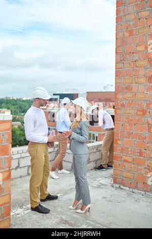 Sorridente supervisori femmina che comunicano con un uomo della casa all'aperto Foto Stock