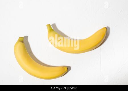 Due banane su sfondo bianco. Banana naturale non pelata intera. Foto Stock