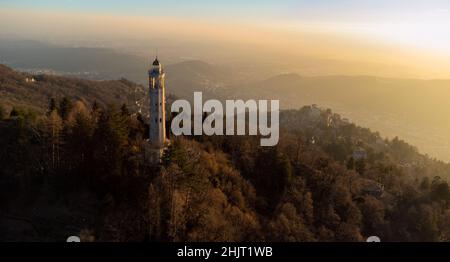 Vista aerea di un faro al centro delle montagne con luce del tramonto - Faro Voltiano (Faro volta) - destinazione di viaggio, Brunate, Foto Stock