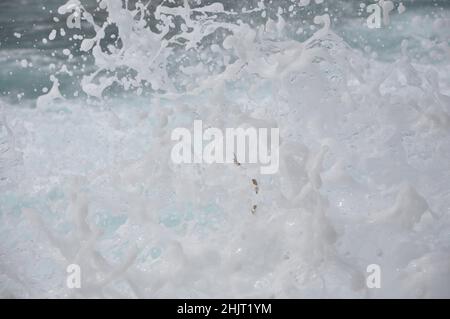 Onde con spruzzi rotolano su una costa rocciosa. Le onde si infrangono su una costa rocciosa della Gulf Coast. Schiuma astratta dal mare che spruzzi sulla roccia Foto Stock