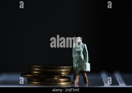 Una figura in miniatura accanto alle monete - concetto di finanza Foto Stock