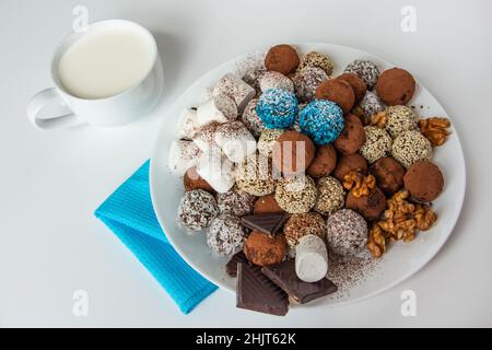 tartufi con cacao, cocco e sesamo, marshmallows, una tazza di latte fresco Foto Stock