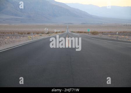 La strada che non finisce mai durante il tramonto nel deserto della Death Valley in California Foto Stock