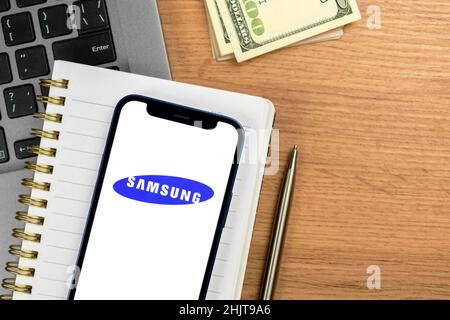 Kharkov, Ucraina - 28 gennaio 2021: Logo Samsung. Sfondo tavolo da lavoro e ufficio con laptop e denaro, vista dall'alto Foto Stock