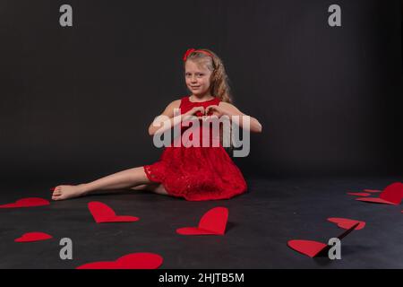 La ragazza si trova felice con un grande cuore San Valentino capretto nero ornamento giorno, per pastello ripetizione in segno da carta da parati vacanza, cuore decorativo. Tessuto Foto Stock