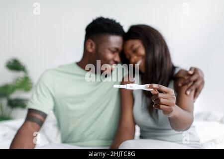 Sorridendo maschio e femmina afroamericano millenario gioire e mostrare test di gravidanza positivo in camera da letto Foto Stock