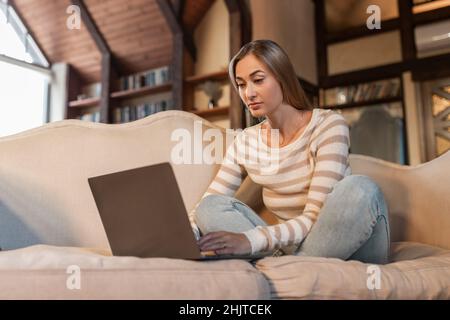 Donna focalizzata che utilizza un notebook per pc a casa Foto Stock