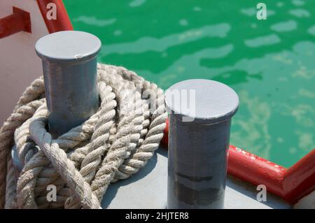 Primo piano di due paludi con corda d'ormeggio di una barca turistica sul lago di Lugano, Svizzera Foto Stock
