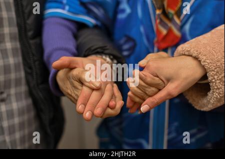 la nonna tiene le mani di un giovane uomo e di una donna. primo piano, mani vecchie. Foto Stock