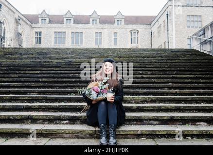 Donna asiatica sedette tenendo fiori e caffè per le strade Foto Stock