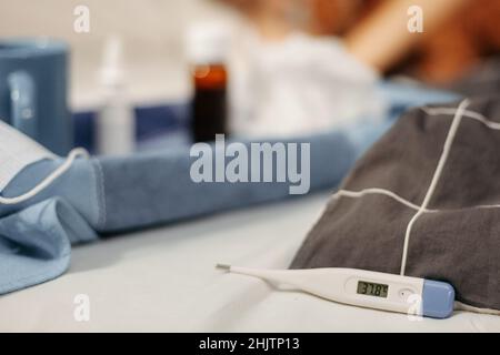 Termometro con numero 38,7 C. primo piano alcuni medicinali sullo sfondo Foto Stock