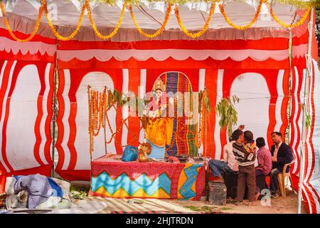 Un colorato santuario indù sulla strada con una statua della dea e delle ghirlande marigolte a Varanasi, una città sul fiume Gange a Uttar Pradesh, nell'India settentrionale Foto Stock