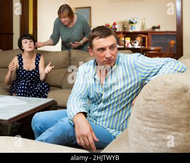 Marito sconvolto a parte sua moglie e madre anziana litigando Foto Stock