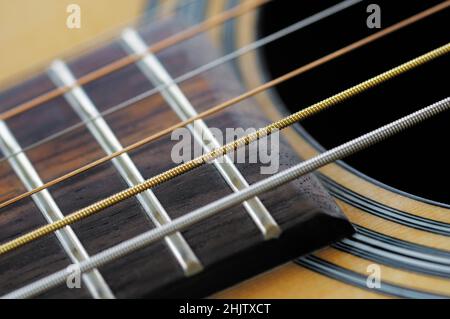 Primo piano dettaglio di corde e tasti di chitarra sulla tastiera (o tastiera) di una chitarra acustica. Foto Stock