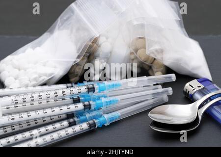 Siringa per iniezione di farmaco ed eroina cotta in un sacchetto su sfondo nero Foto Stock
