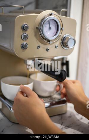 Le mani femminili tengono due tazze bianche di porcellana che cucinano fragranza aroma caffè del mattino in macchina Foto Stock