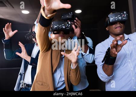 Amici multiculturali che utilizzano cuffie per realtà virtuale Foto Stock