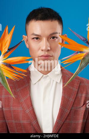 Ritratto di uomo serio in giacca tuta a in piedi tra due fiori gru Foto Stock