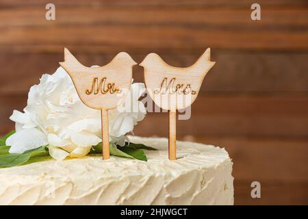 Bella torta nuziale con topper su sfondo di legno Foto Stock